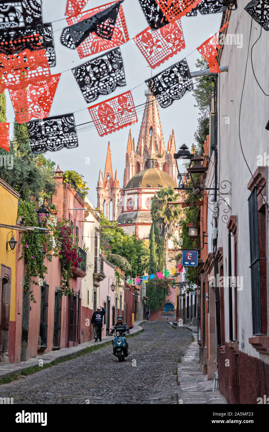 Domes and spires of the Parroquia San Miguel Arcangel church seen through paper banners called papel picado strung to celebrate the Day of the Dead festival on Aldama Street in the historic district of San Miguel de Allende, Mexico. Stock Photo