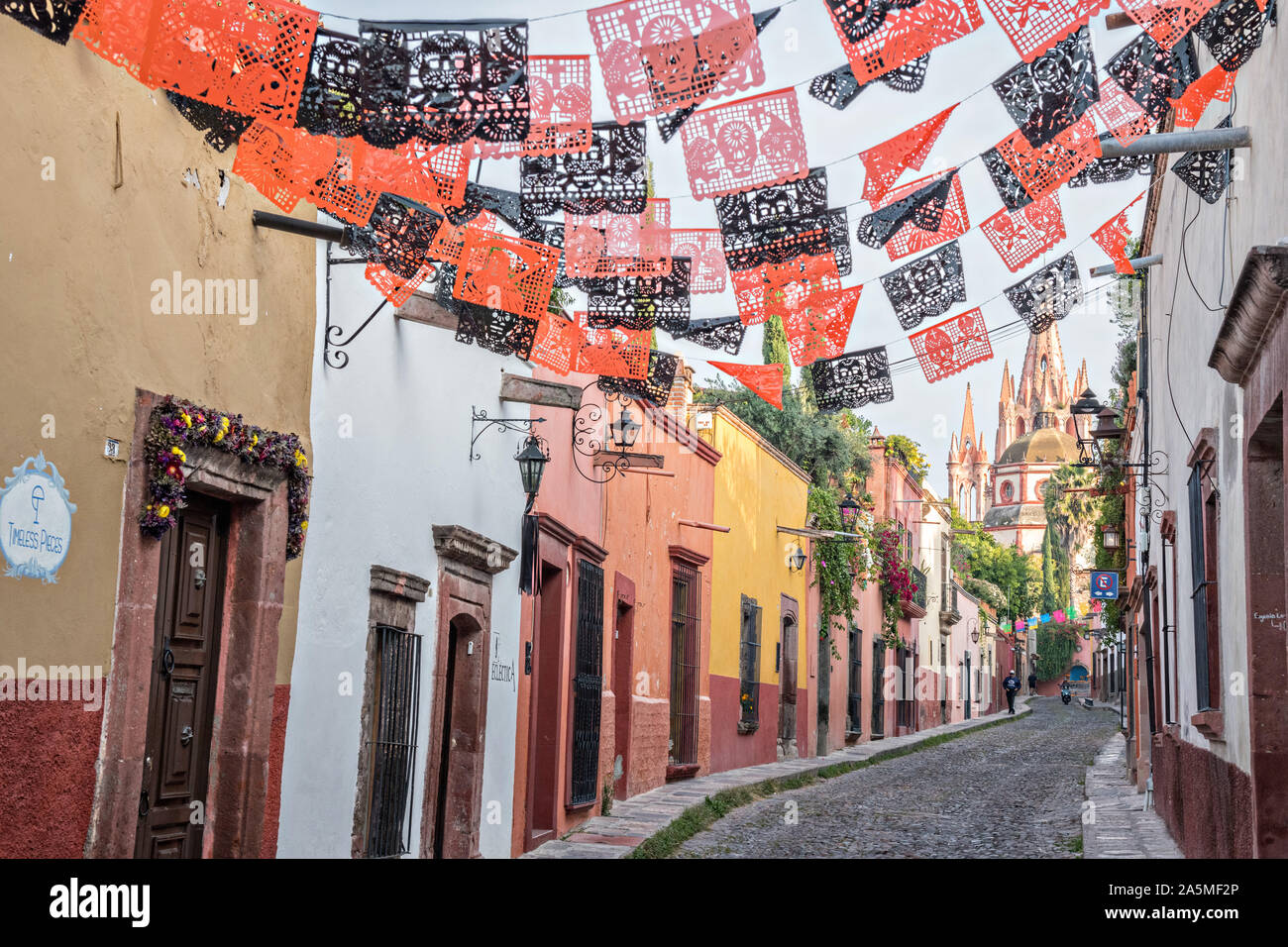 Domes and spires of the Parroquia San Miguel Arcangel church seen through paper banners called papel picado strung to celebrate the Day of the Dead festival on Aldama Street in the historic district of San Miguel de Allende, Mexico. Stock Photo
