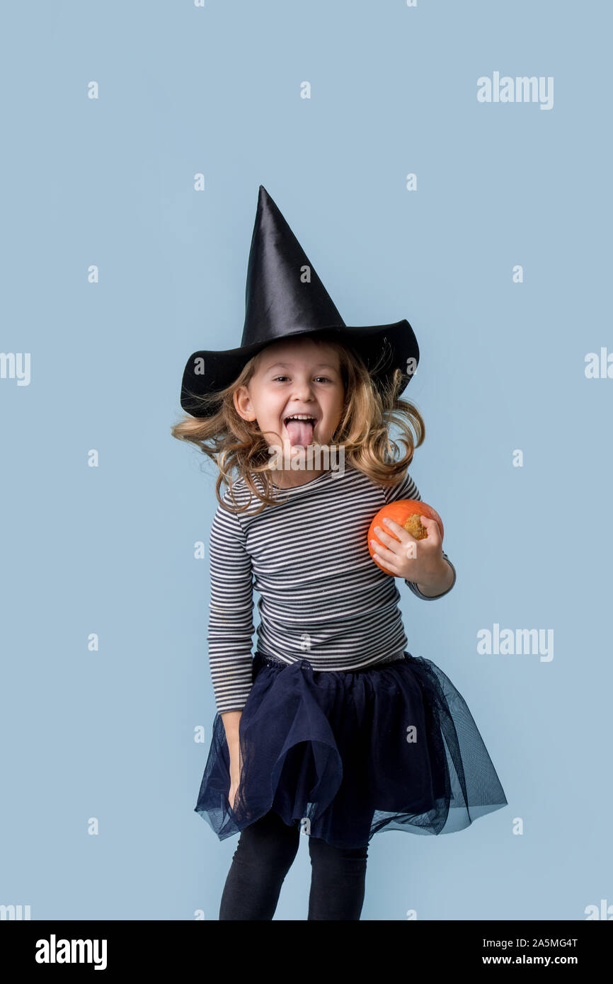 Little girl with a pumpkin in hands and in a witch costume Stock Photo ...