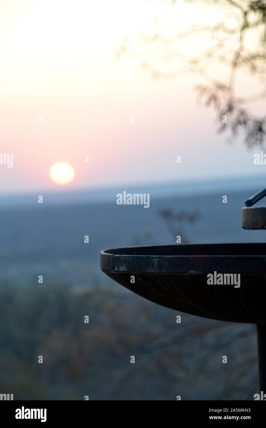 Charcoal braai BBQ fireplace framed by a bush veld sunrise in Kruger National Park in South Africa Stock Photo