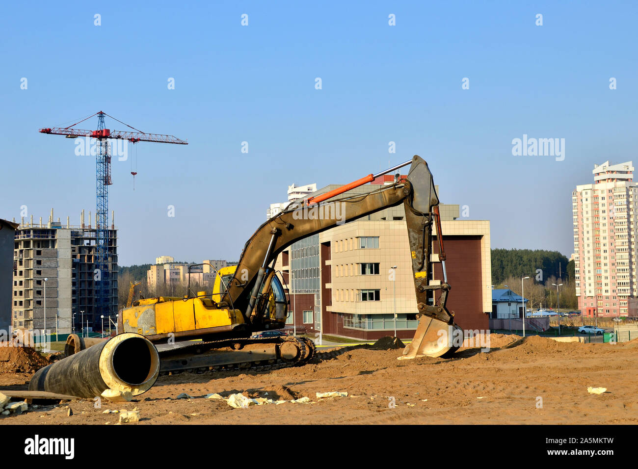 Yellow excavator at a construction site during earthworks and laying of ...