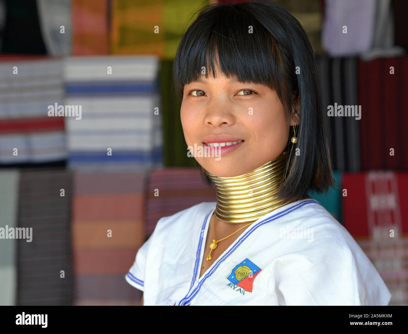 Young Myanmarese Kayan Lahwi longneck woman (“giraffe woman”) with tribal Padaung brass neck rings/coils smiles for the camera. Stock Photo