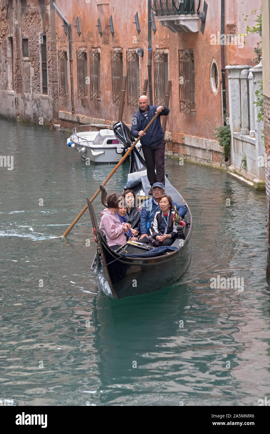 A group of Asians, likely Chinese, take a gondola ride on the Grand Canal in Venice, Italy. From the Rialto Bridge, Stock Photo