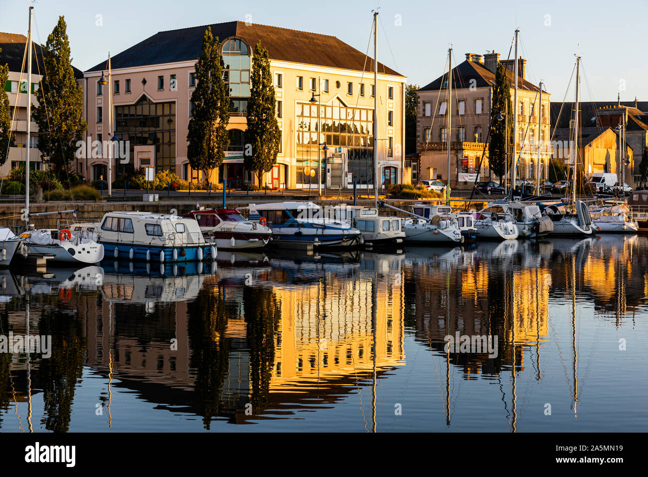 Early morning sun catches the front of  buildings around the yacht basin at Redon, France Stock Photo