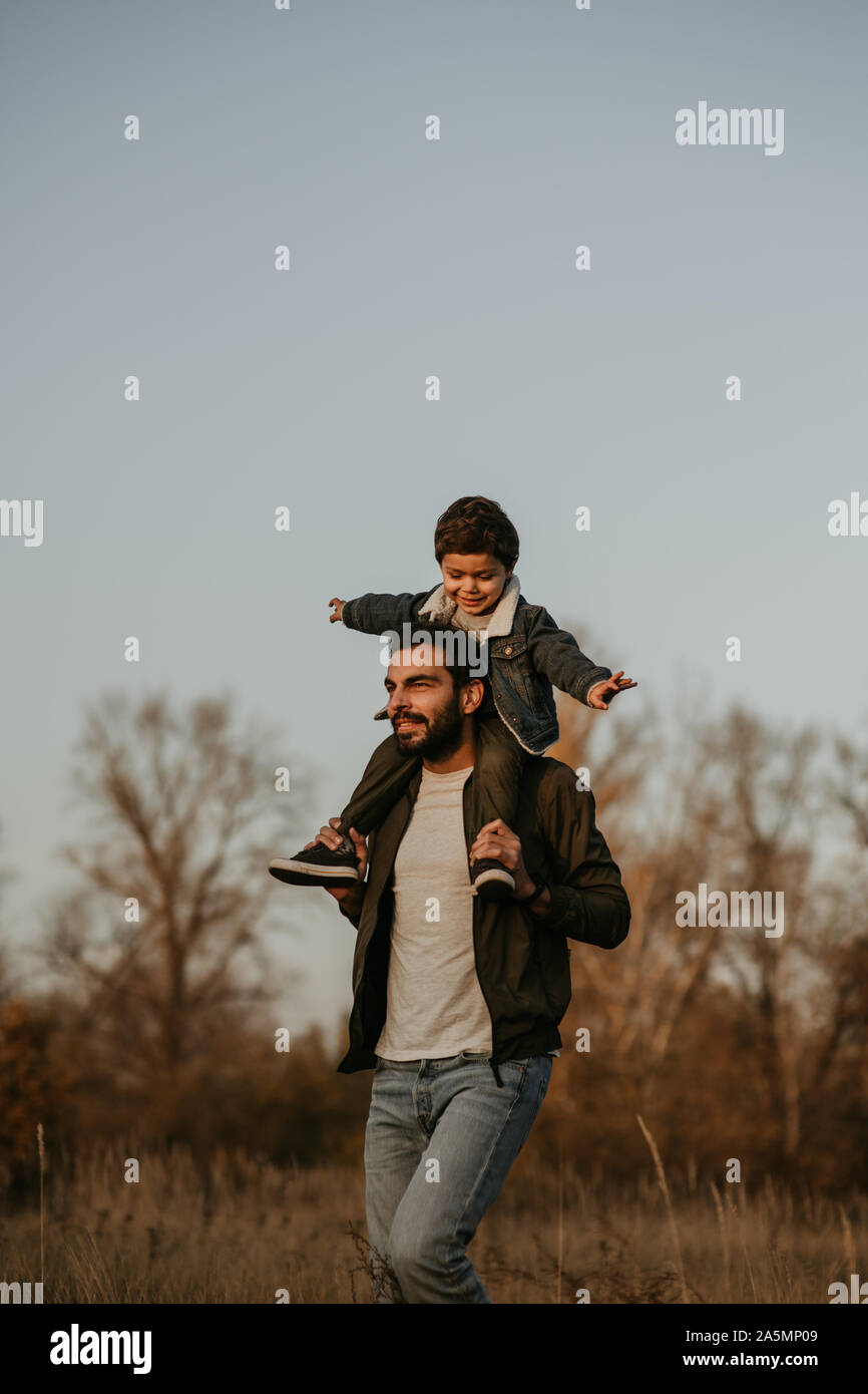 Happy father giving son ride on his shoulders during countryside walk. Stock Photo