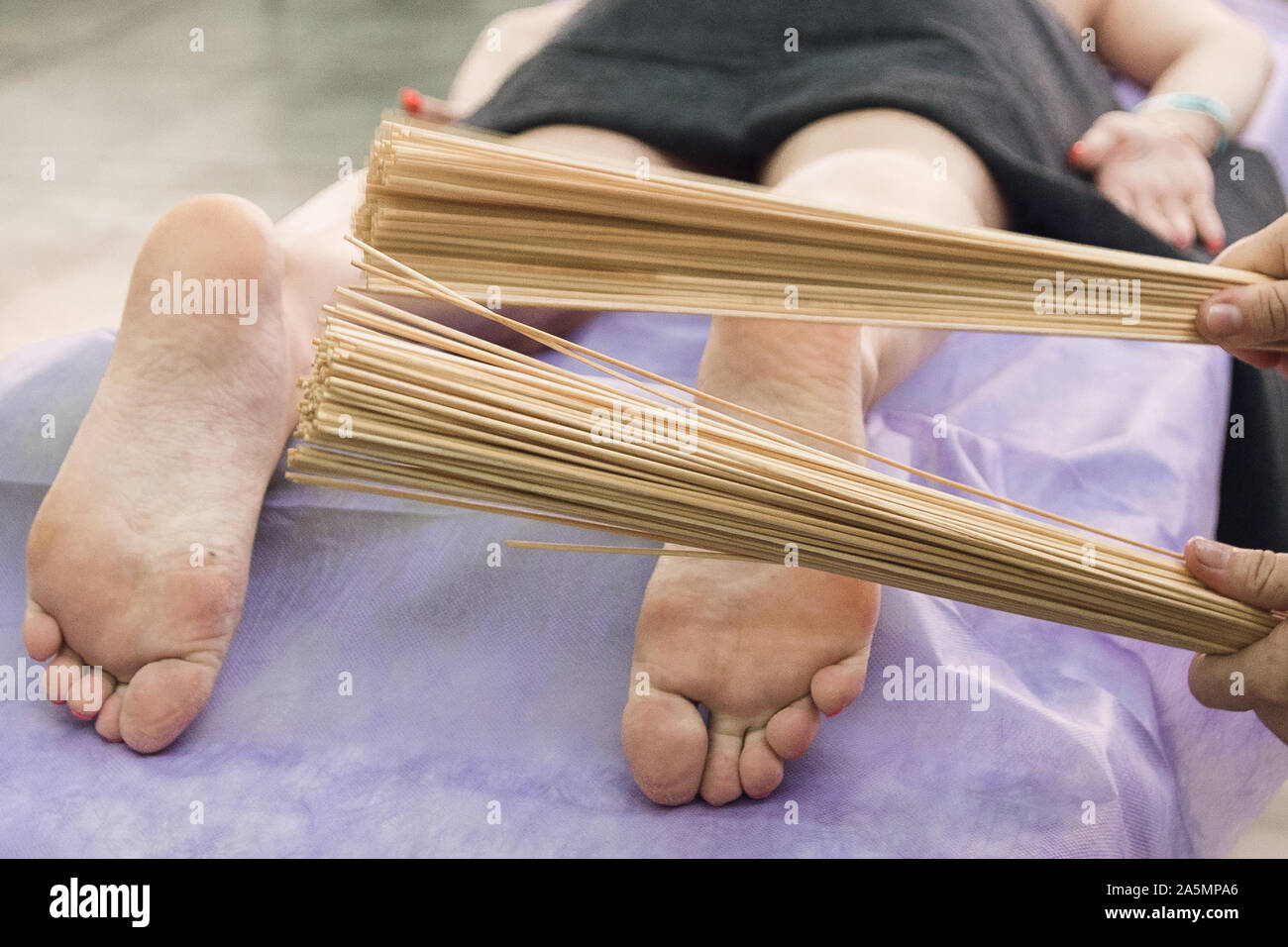 Massage with bamboo sticks of feet. 