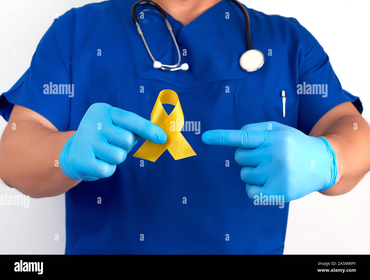 doctor in a blue uniform and sterile latex gloves holds a yellow ribbon in his hand, a symbol of the fight against the cat's tumor, problem of suicide Stock Photo