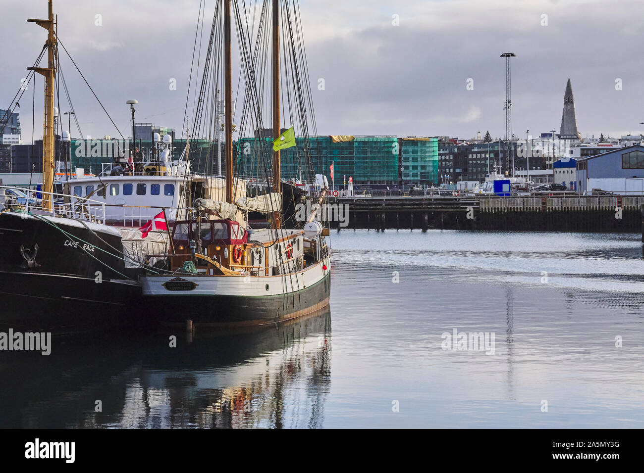 View over the old harbour in Reykjavík, Iceland, fishing boats in foreground, and dramatic seafront skyline Stock Photo