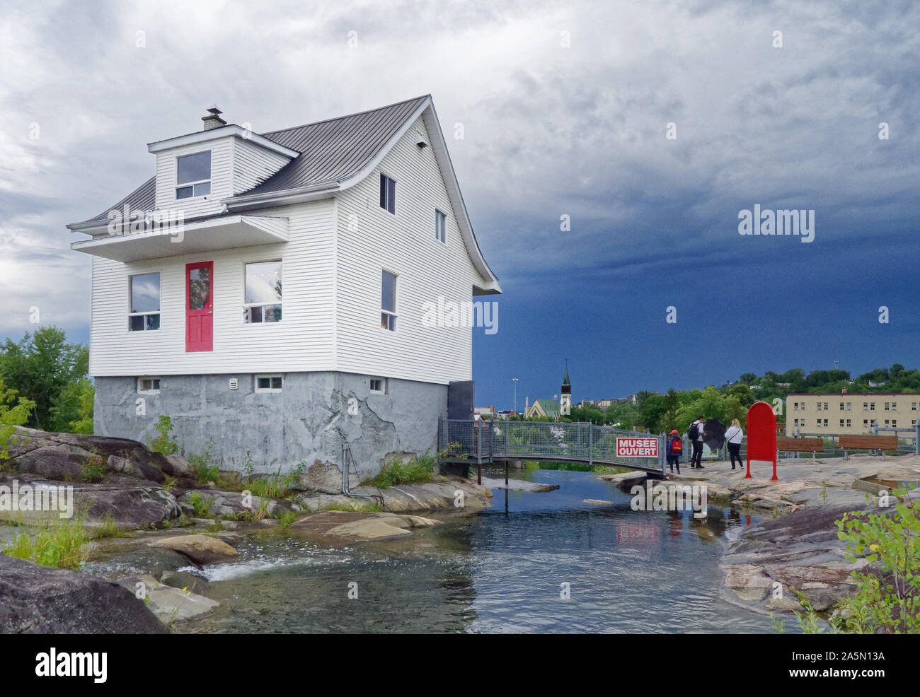 The famous little white house (La Petite Maison Blanche) in Saguenay that withstood the 1996 flooding, with stormy skies beyond Stock Photo