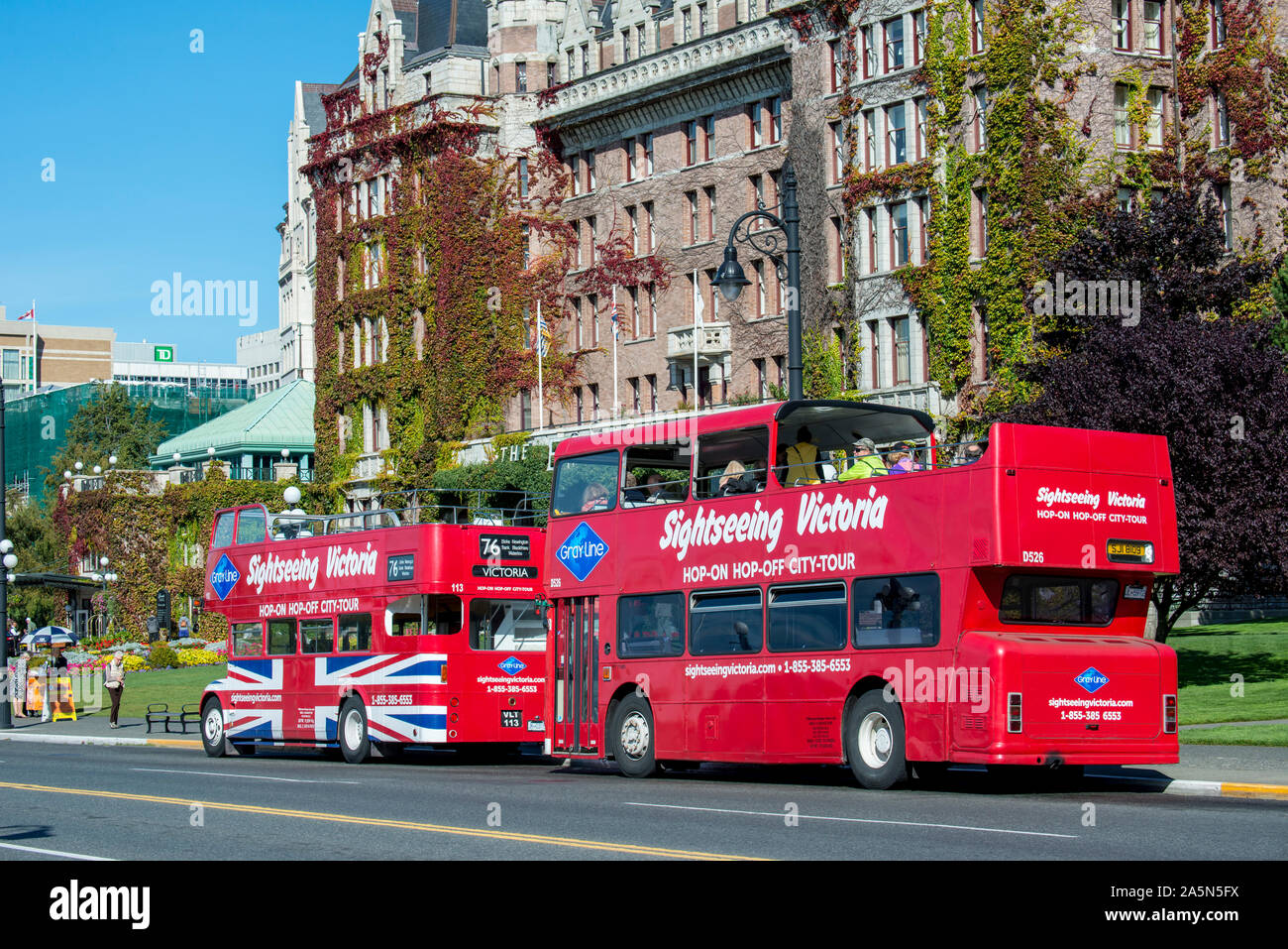 Victoria, British Columbia, Canada.   Two double decker sightseeing buses with tourists parked in front of the Empress hotel. Stock Photo