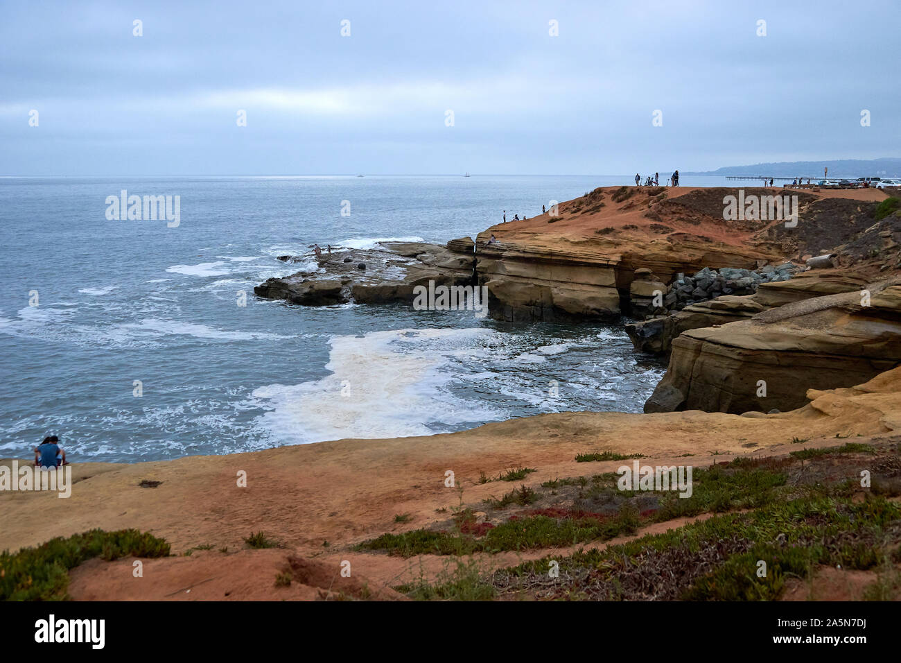 A multitude of people, tourists, including a couple, standing, walking or sitting on beach cliffs at Sunset Cliffs, San Diego, California Stock Photo