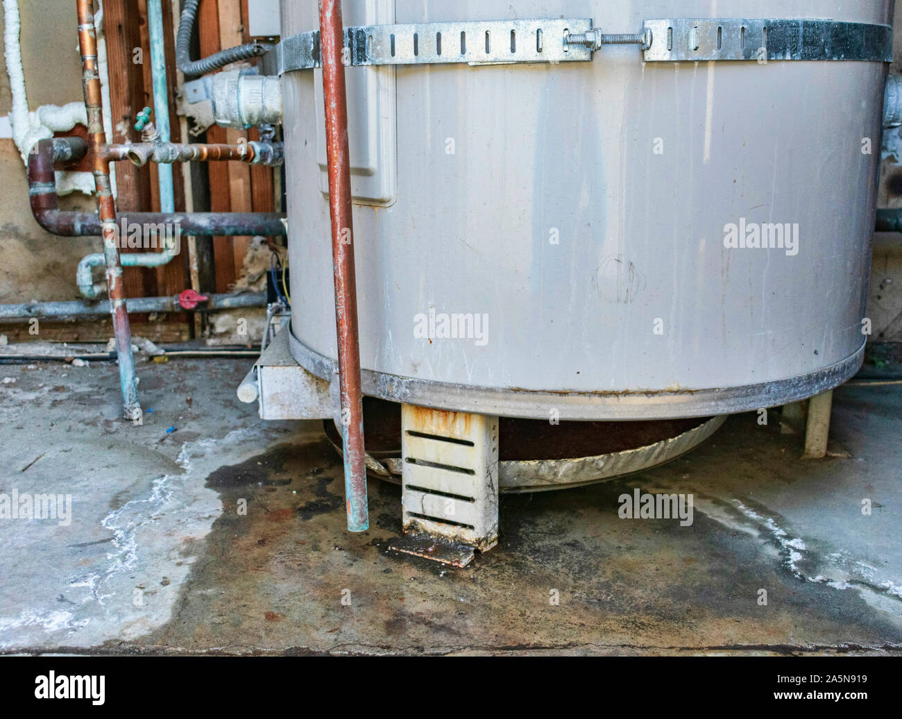 Water heater leaks from the bottom to the floor. Overflowing water heater drip pan. The plumber service for inspection, repair or replacement Stock Photo