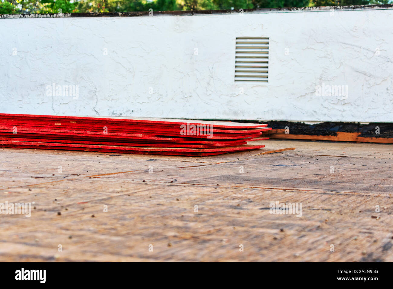 Flat roof repair and replacement in progress. Sheets of stacked plywood on roof sheathing. Stock Photo