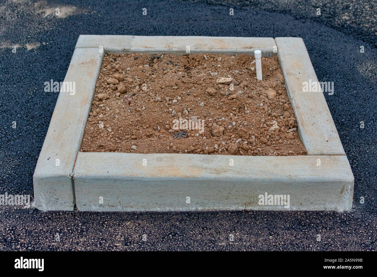 Construction of surface parking lot island. Fresh asphalt. Irrigation system for parking lot island green landscaping. Stock Photo