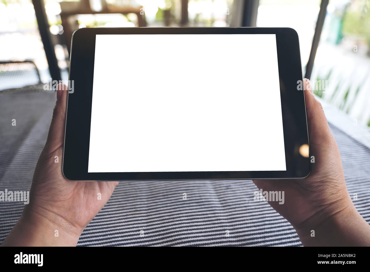 Mockup image of hands holding black tablet pc with blank white desktop ...