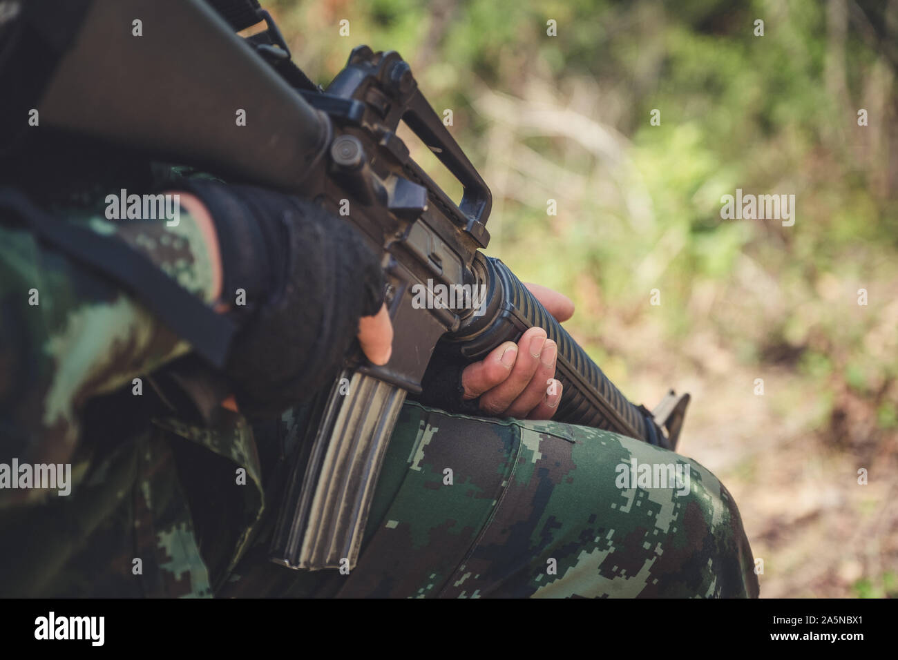 Closeup image of an armed soldier holding his gun in the battle field Stock Photo