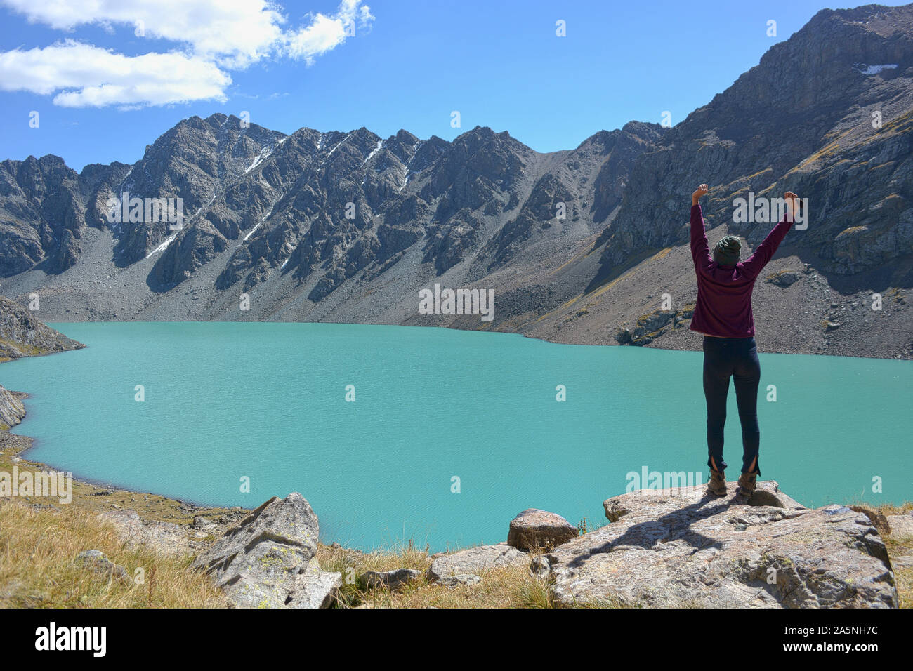 Girl near beautiful mountain lake. Ala-Kul lake in Terskey Alatoo mountains, Tian-Shan, Karakol, Kyrgyzstan Stock Photo