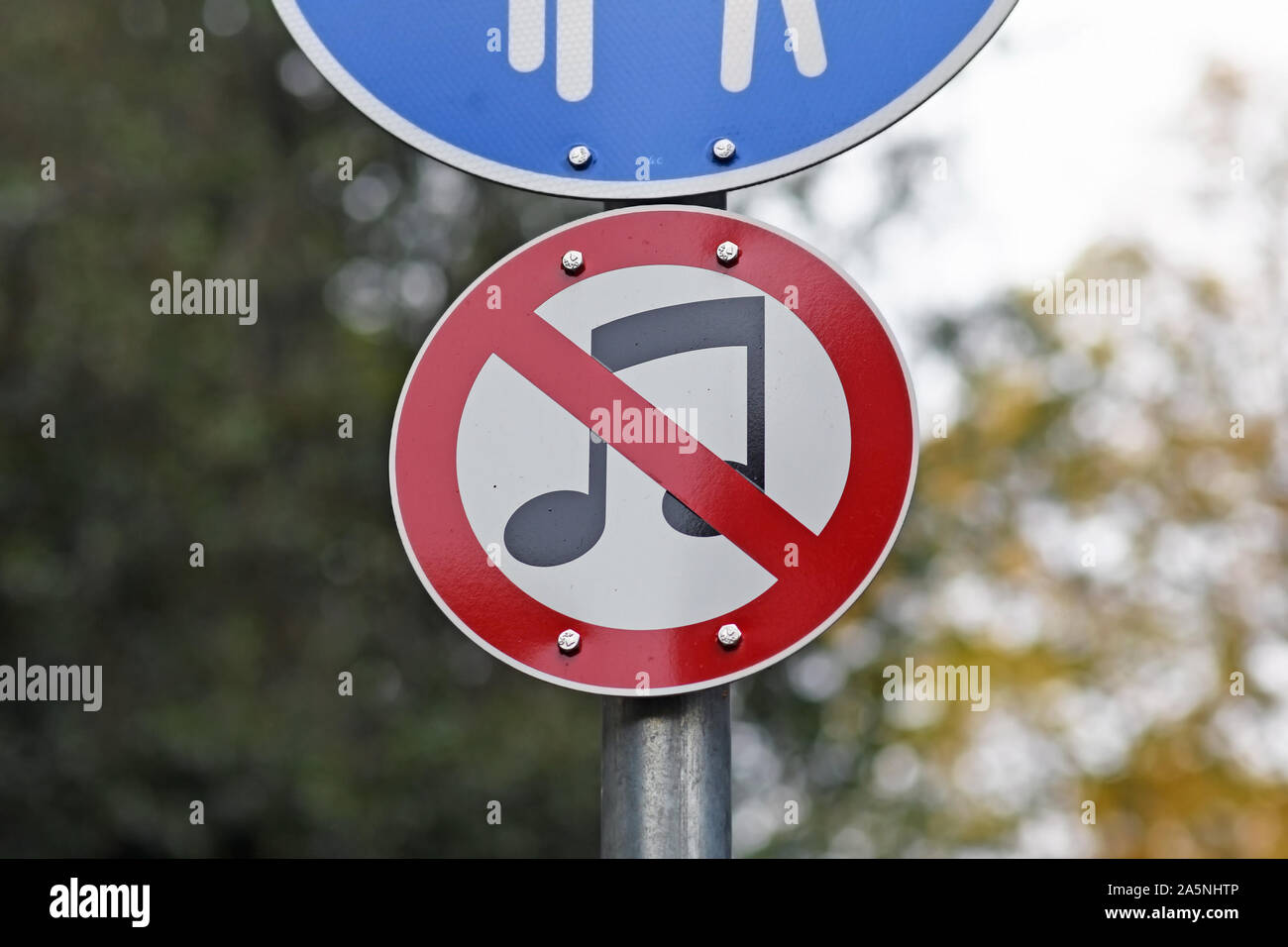 Unusual round street sign with music notes crossed out in red, forbidding playing or listening to music in public park in Germany Stock Photo