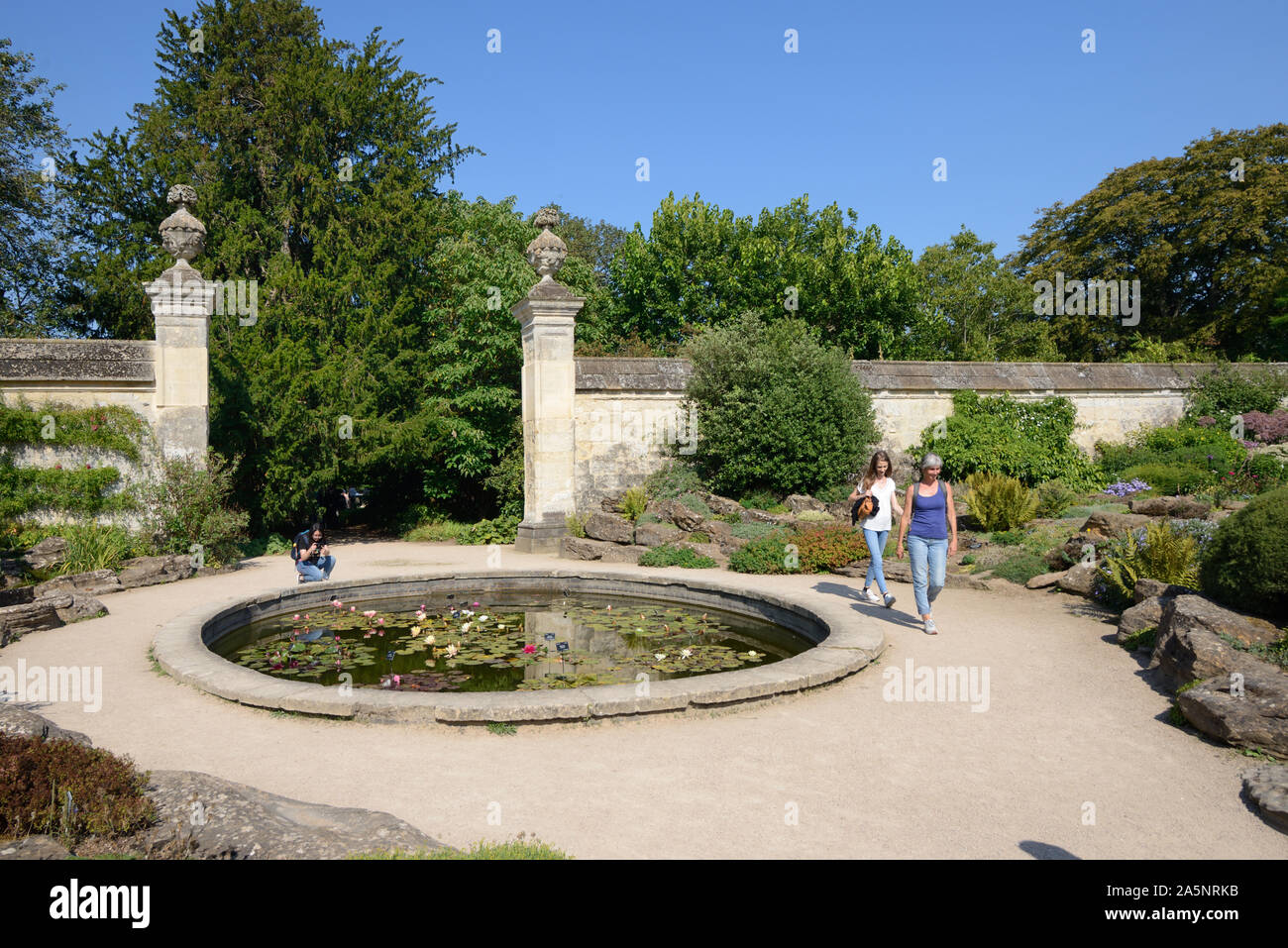 Tourists & Round Pool or Pond & Gate to the Walled Garden University of Oxford Botanic Garden Oxford England Stock Photo