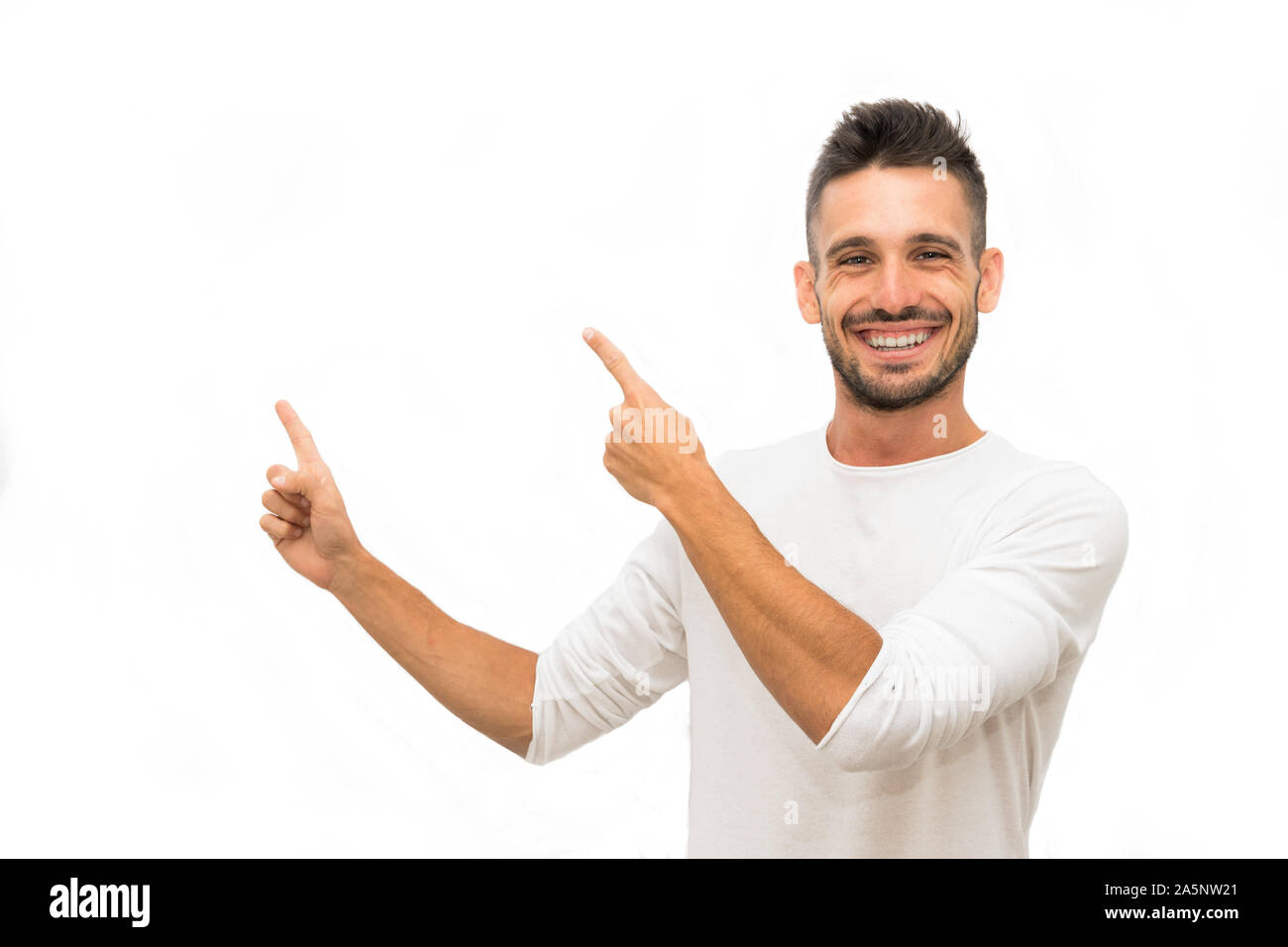 Young causal man wearing a white t-shirt over isolated white background amazed and smiling to the camera while presenting with hand and pointing with Stock Photo