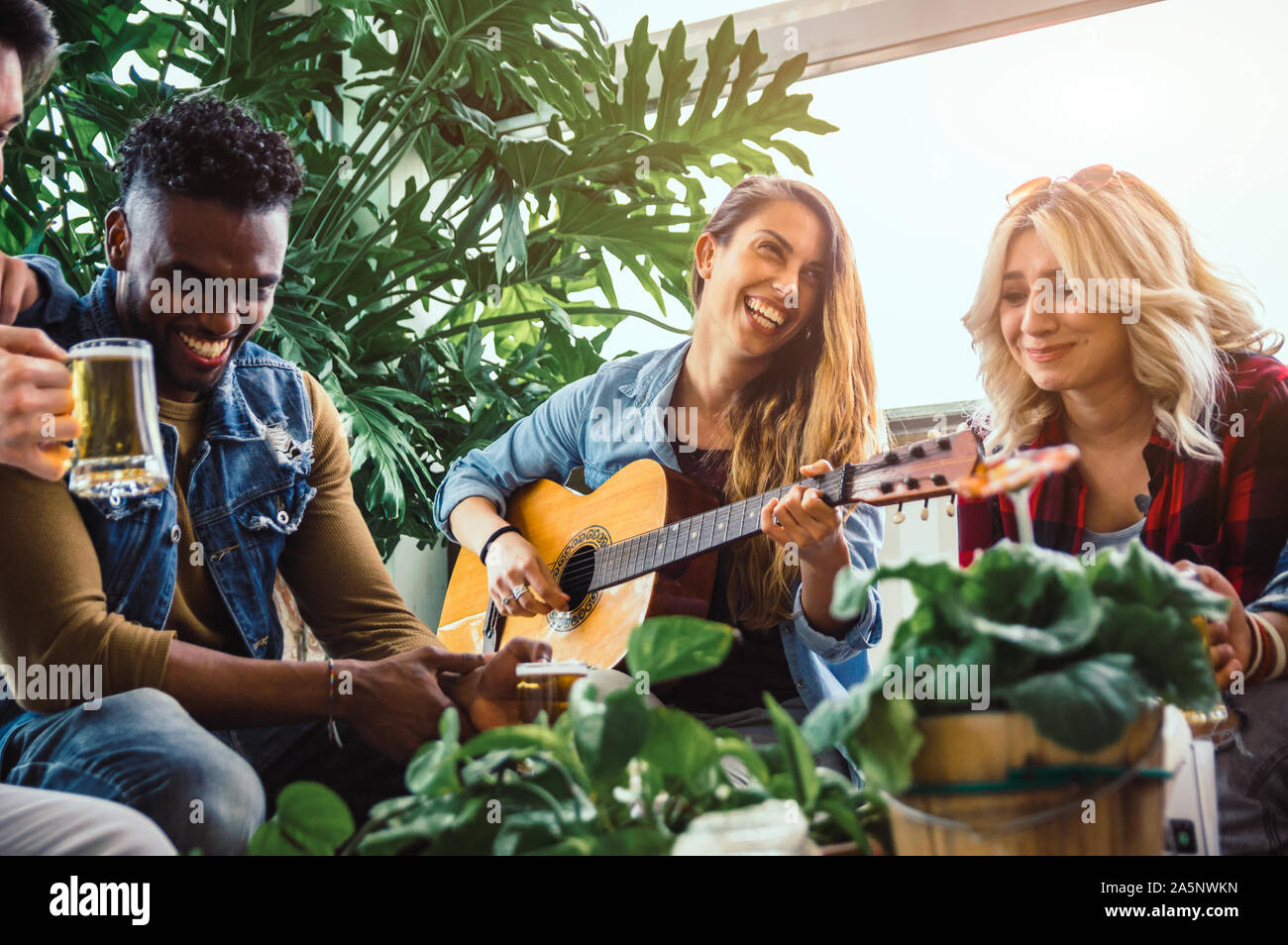 Group of multiracial friends having fun playing guitar drinking beer on vacation Stock Photo