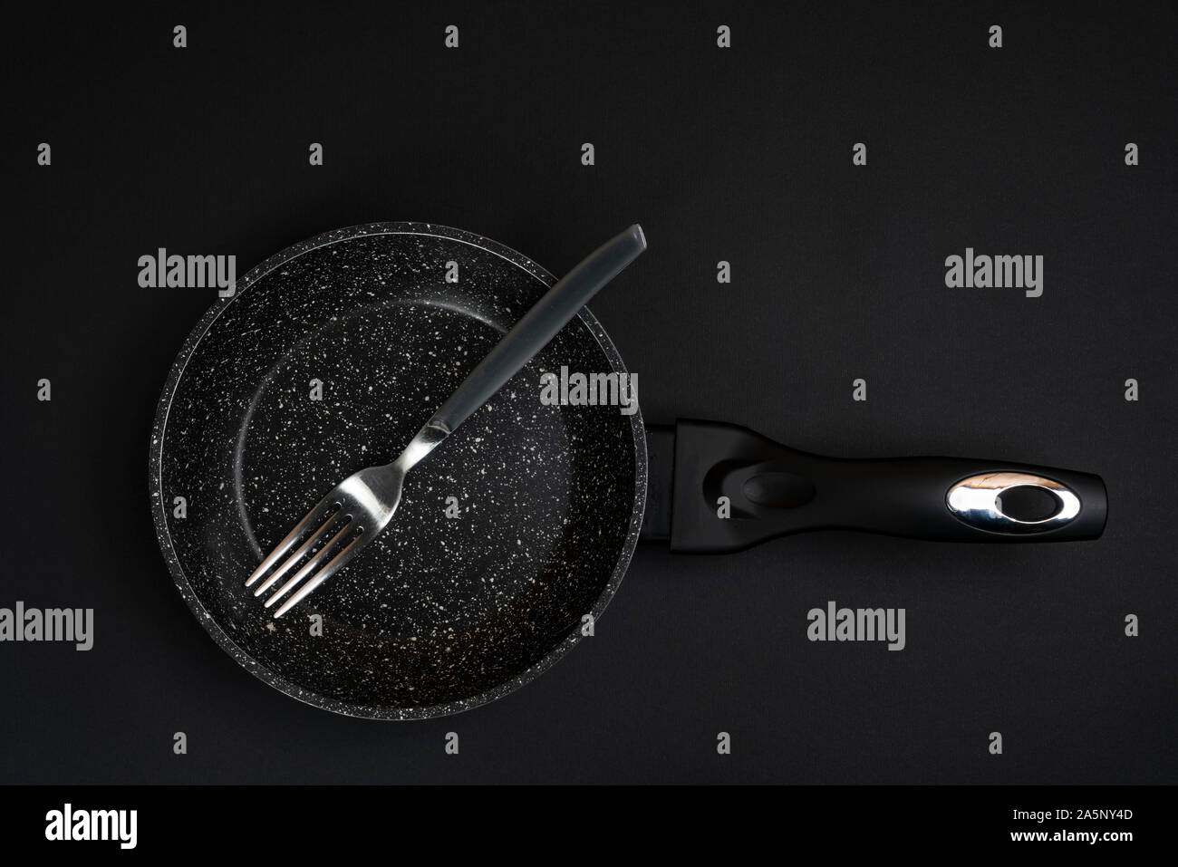 a fork in a pan on a black surface Stock Photo