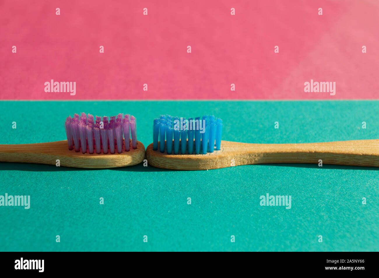 Two colorful bamboo wooden toothbrushes on green and pink background ...