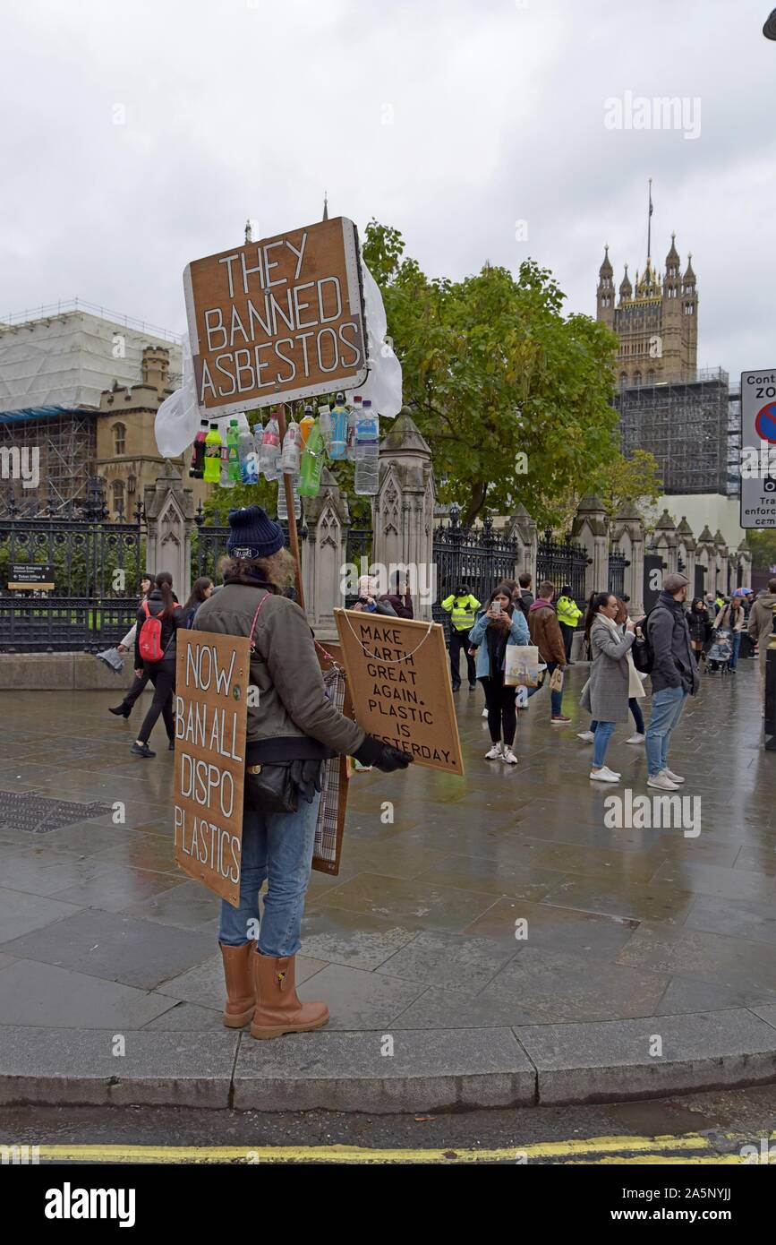 A campaigner for the banning of plastics stands outside the Houses of Parliament with placards and a plastic bottle display. 21st October 2019 Stock Photo