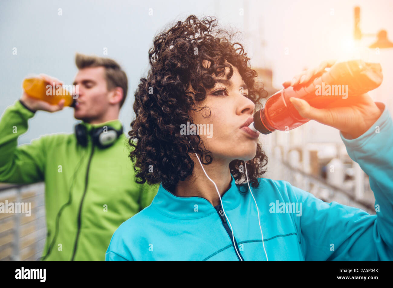 Man and woman drinking energy drink from bottle after fitness sport