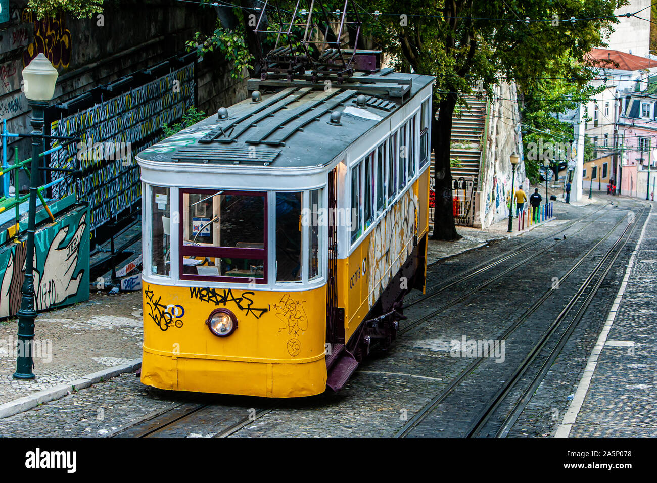 A yellow tram descends the hill towards the centre of Lisbon, Portugal Stock Photo