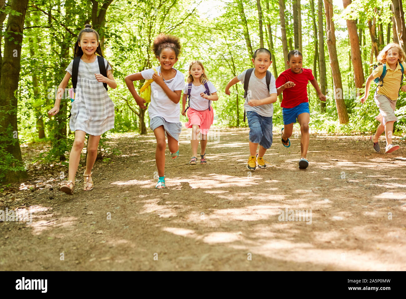 Group of kids with backpacks racing in the nature in summer on a tour Stock Photo