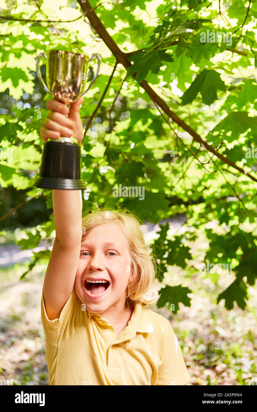 Boy with a winner's cup cheers exuberantly over a victory in the competition Stock Photo