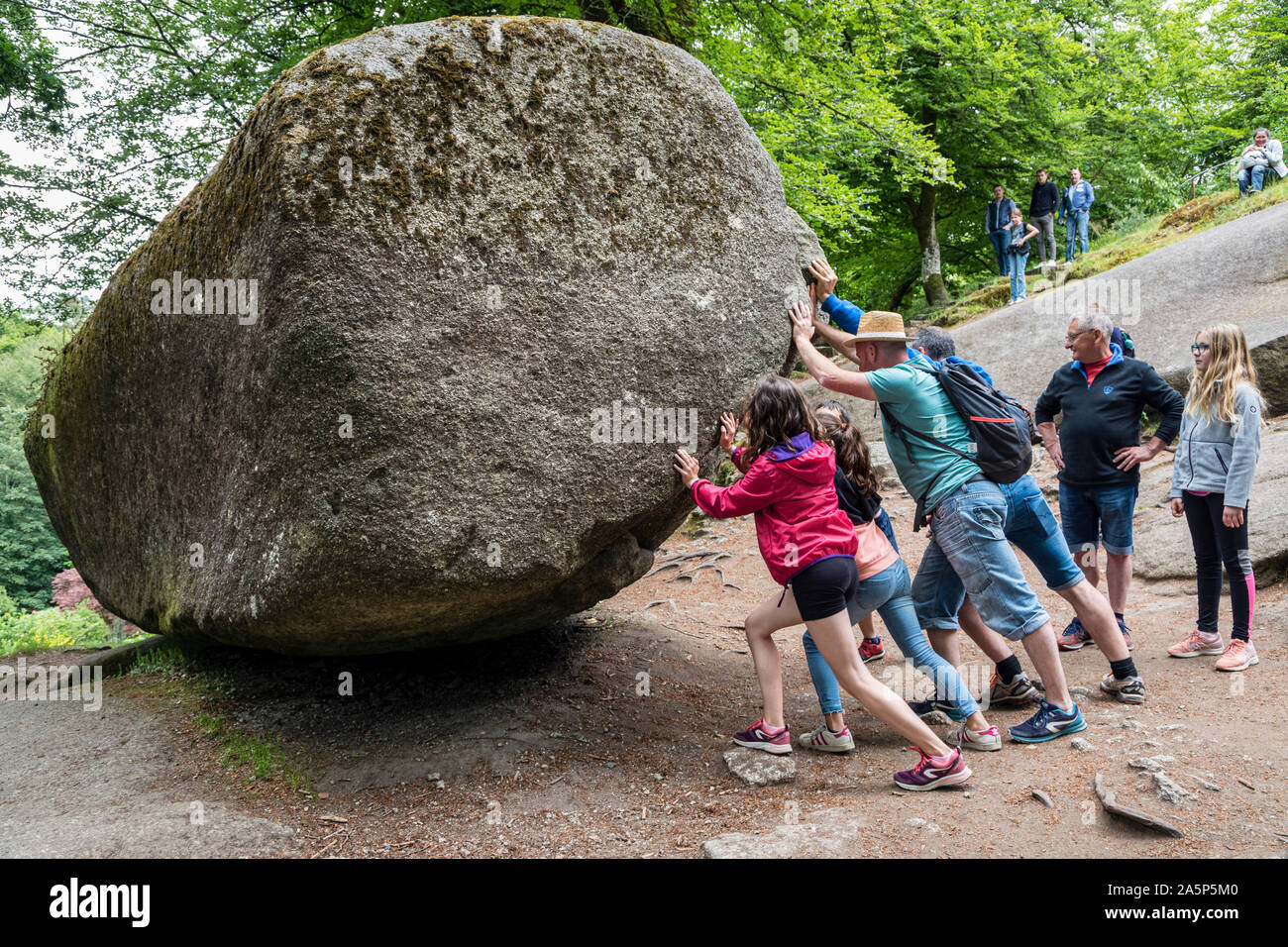 Visitors trying to rock La Roche Tremblante, Huelgoat, Brittany, France Stock Photo