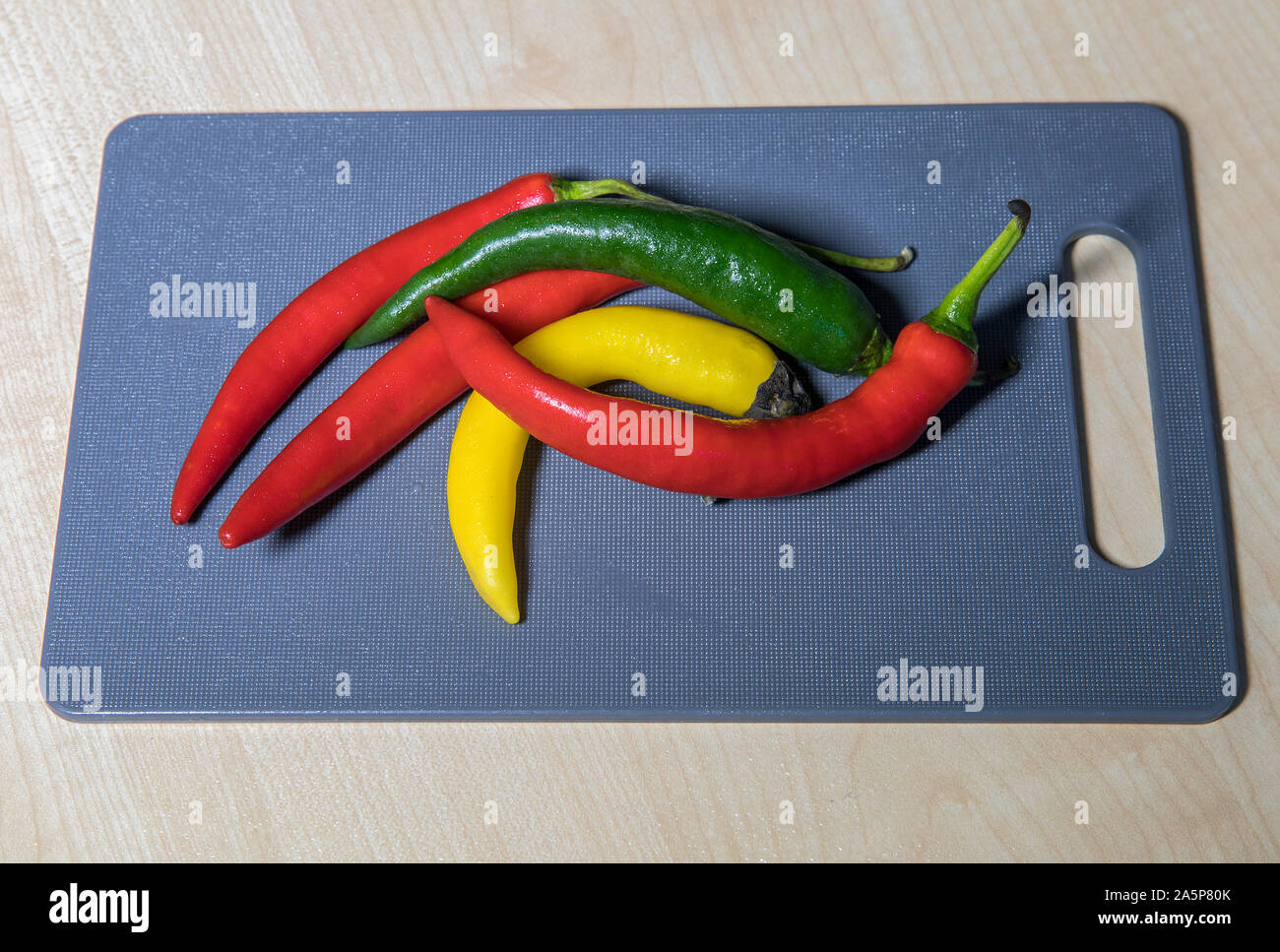 Chili Peppers. Multi coloured hot chili peppers on cutting board . Stock Image. Stock Photo