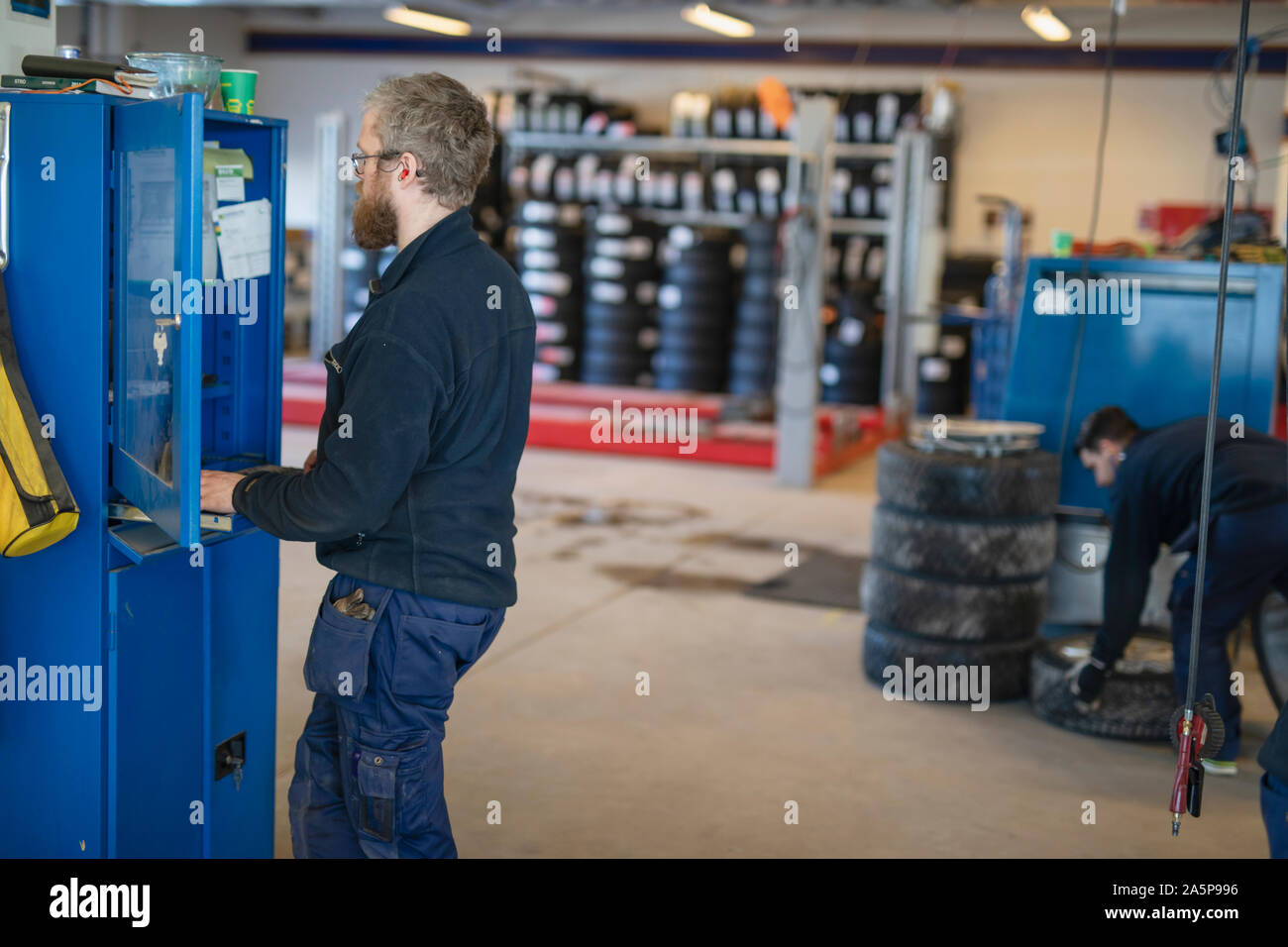 Car mechanic using computer in garage Stock Photo