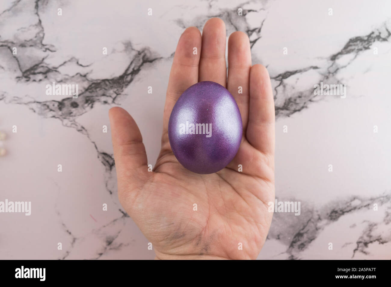 Marble Easter flat lay background with painted Easter egg in female hand. Stock Photo