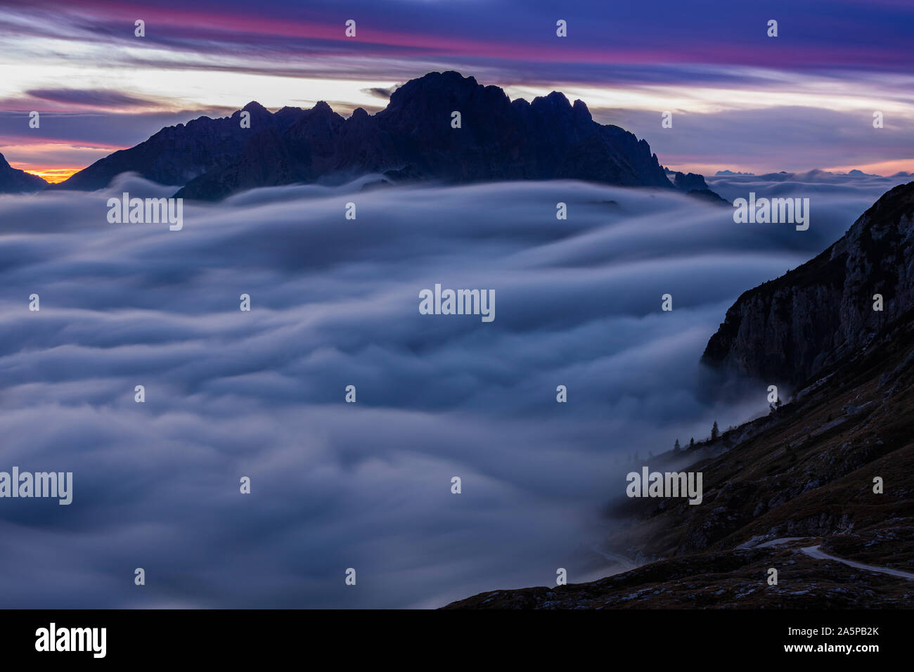 Clouds moving over mountain tops at sunset Stock Photo