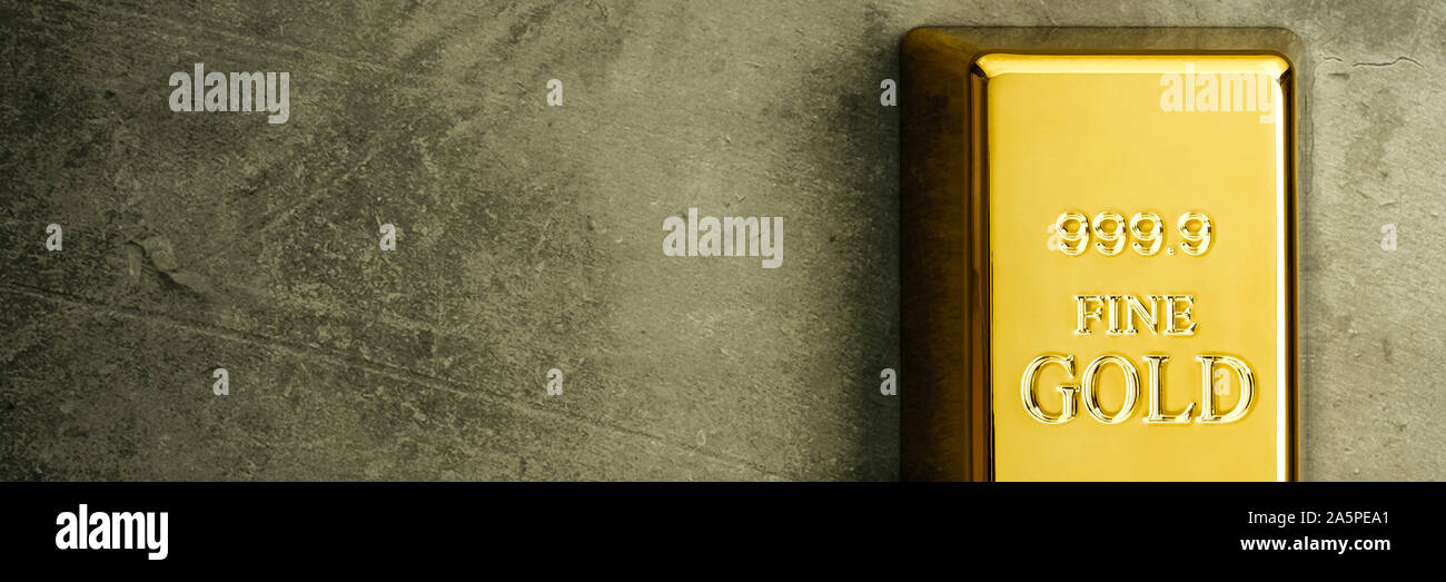 Ingot of pure gold metal bullion on a gray textured background Stock Photo