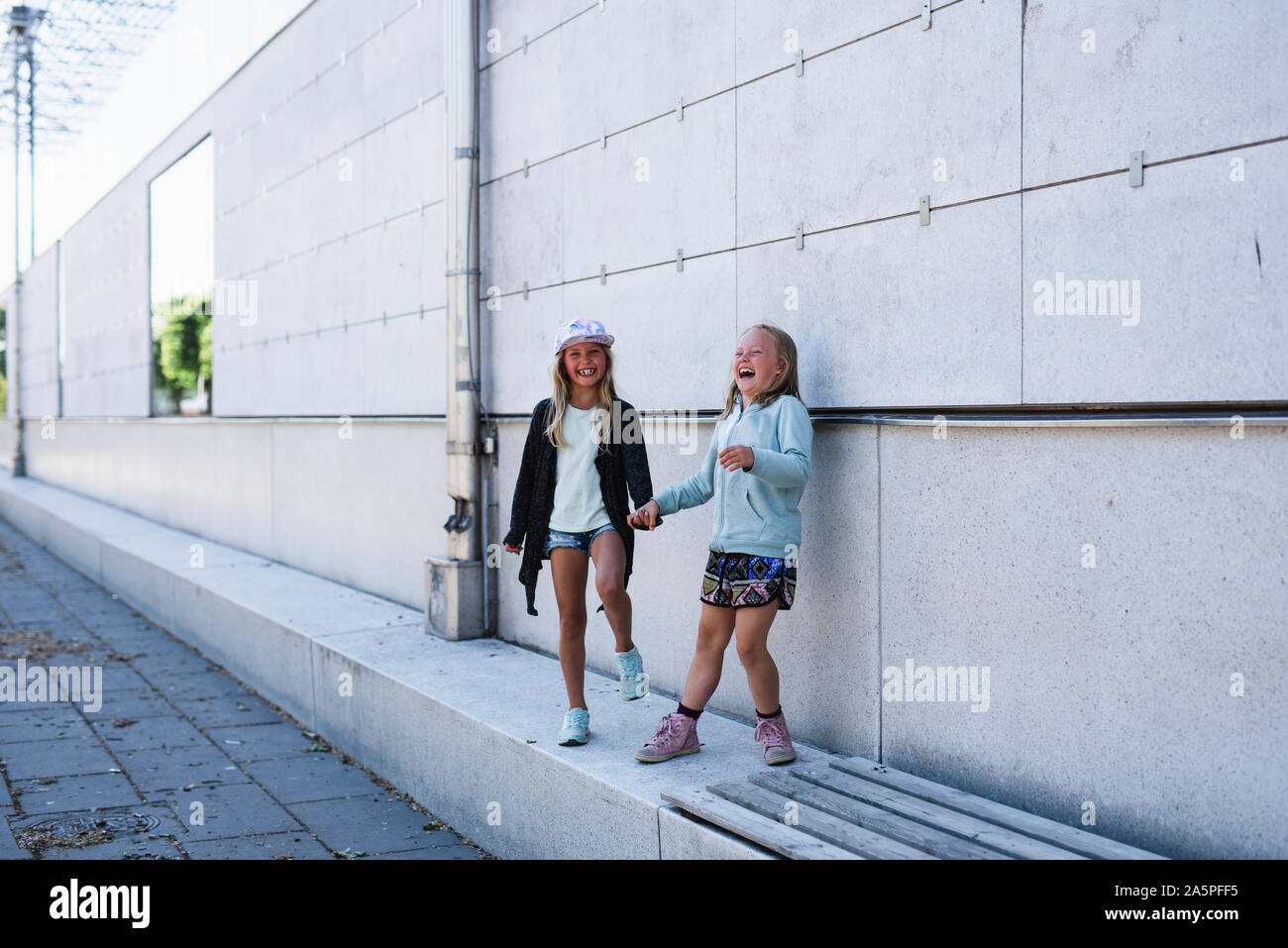 Two girls standing by wall Stock Photo