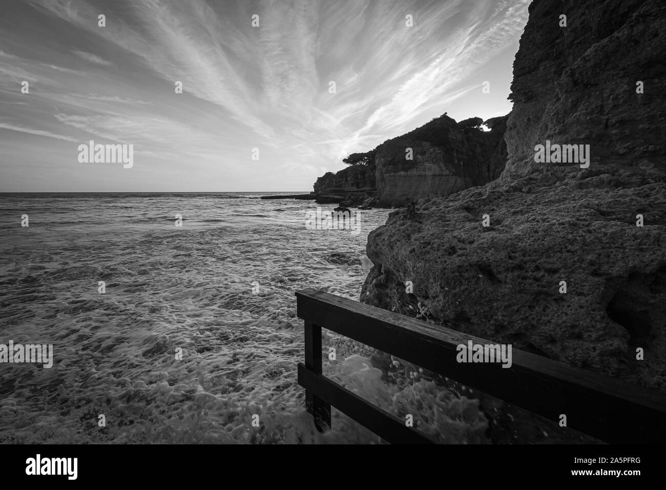 High tide at the beach at Olhos D'Agua in the Algarve on the south coast of Portugal. Black and white Stock Photo