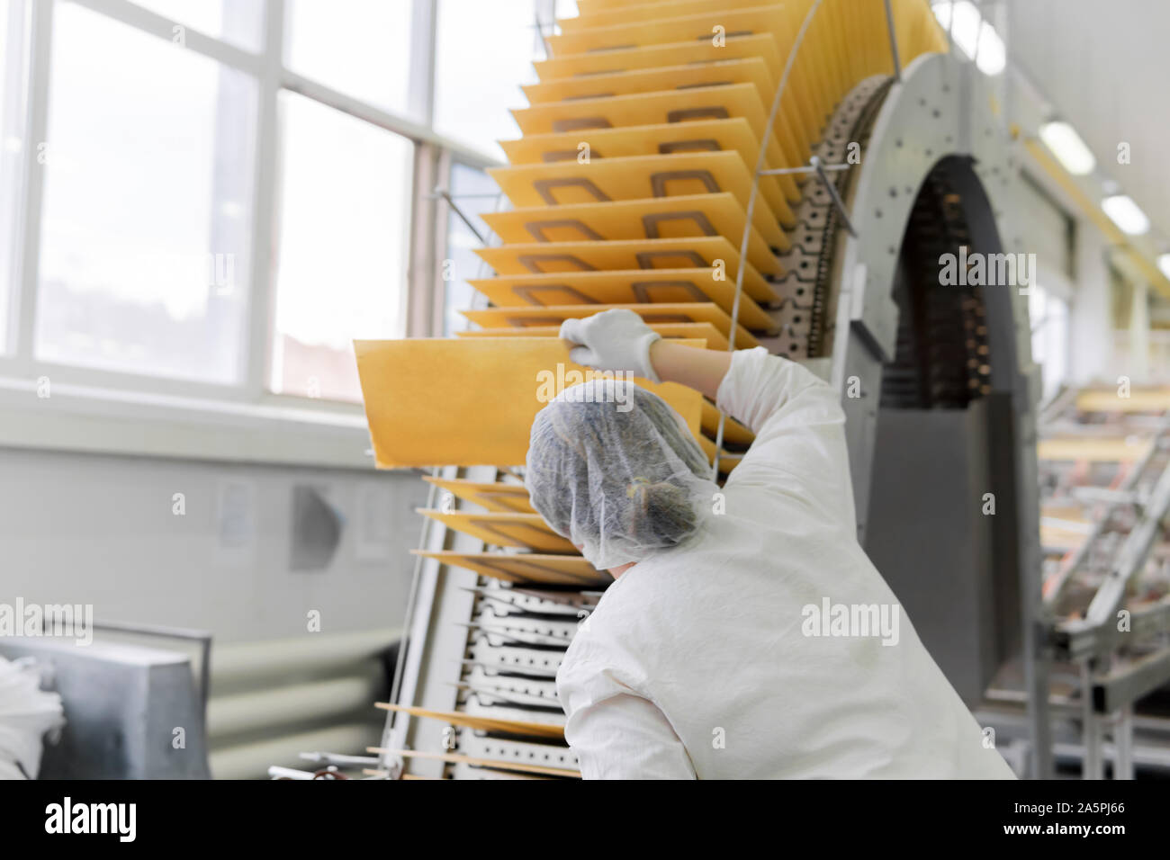 the confectioner-technologist controls the quality of baking wafers on the conveyor in the shop of the confectionery factory Stock Photo