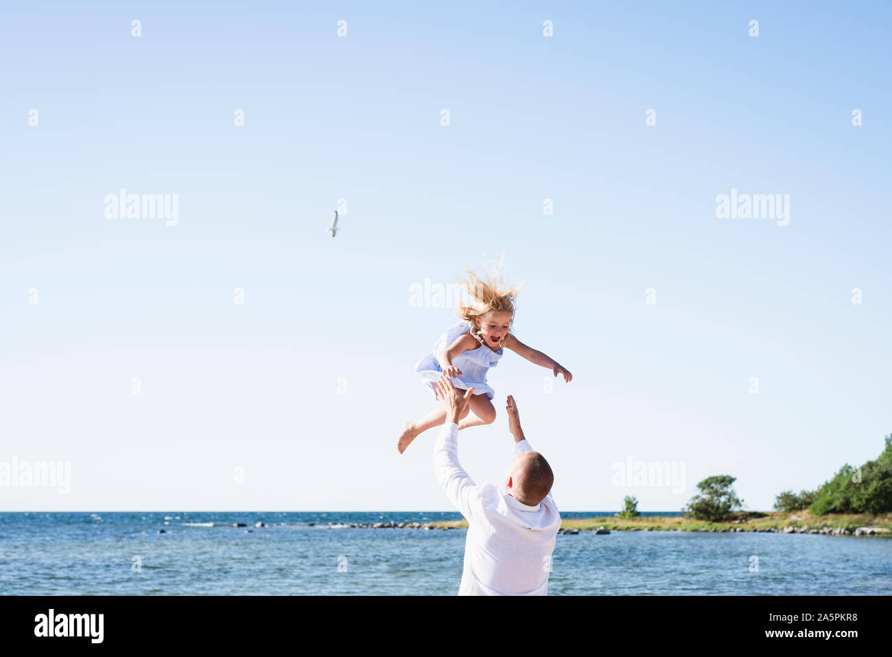 Father playing with daughter on beach Stock Photo