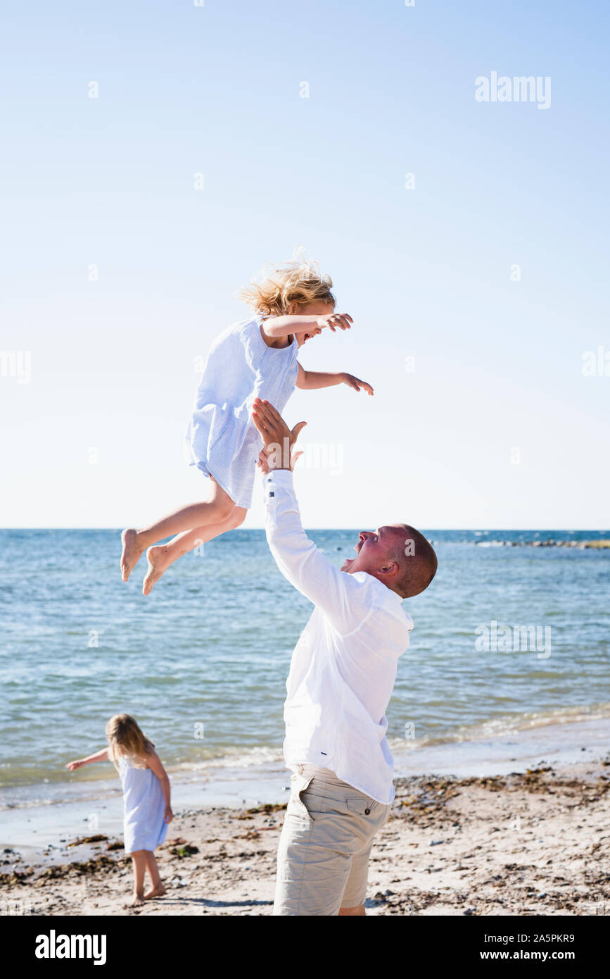 Father playing with daughter on beach Stock Photo