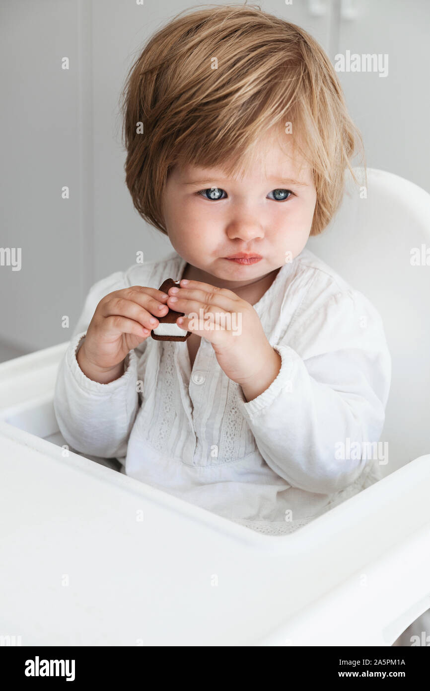 Baby girl sitting on high chair Stock Photo Alamy