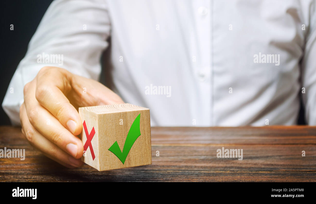 Businessman holds a wooden block with a green check mark. The concept of choice and making the right decision. Business management. Plan, planning. Re Stock Photo