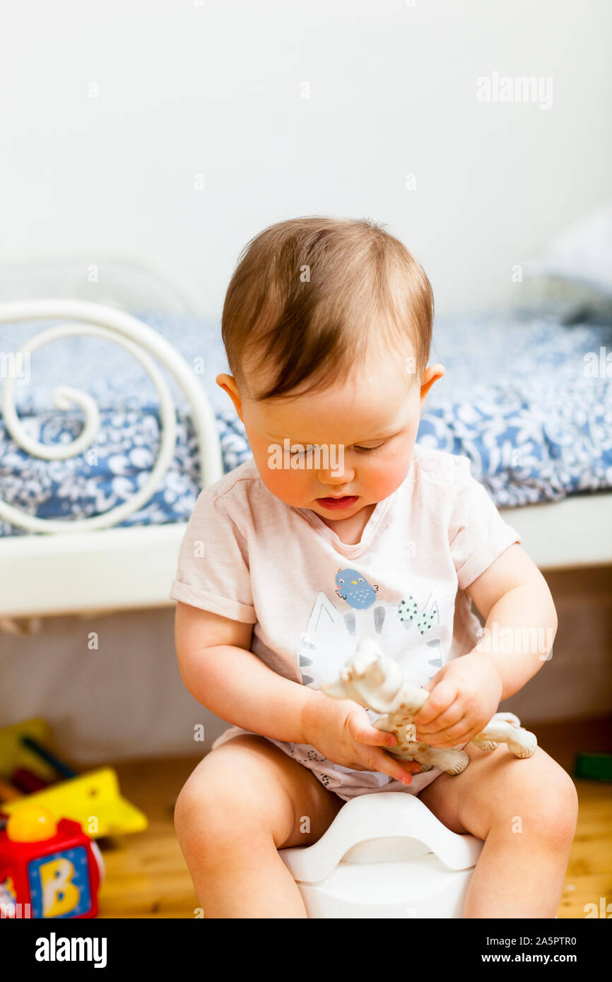 Baby girl sitting on potty Stock Photo
