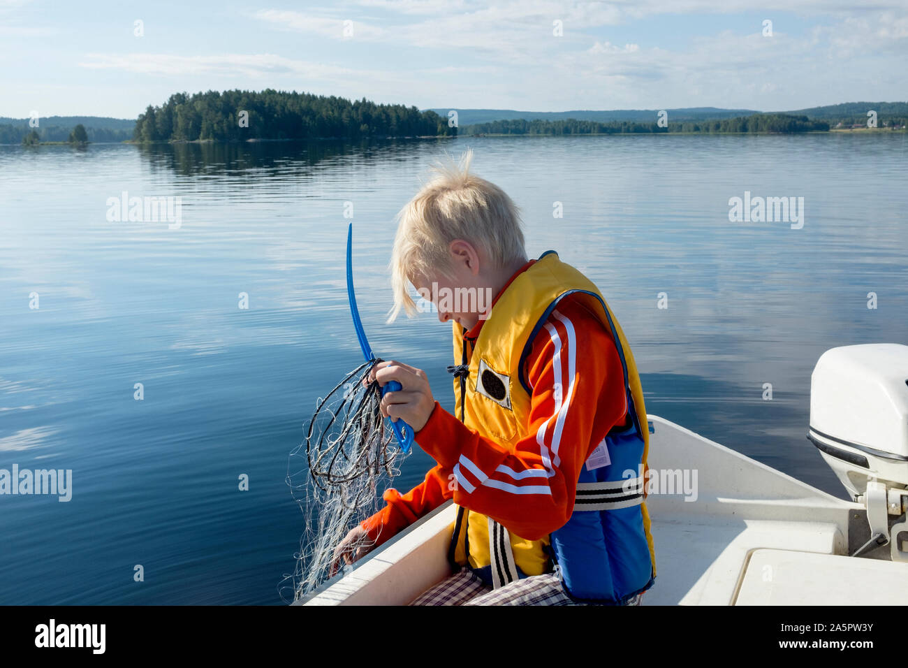 Boy pulling net out of water Stock Photo