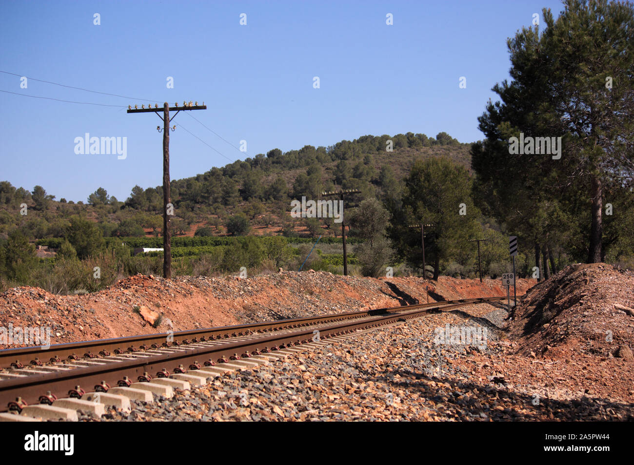 Landscape from a curve in the conventional train track that runs between the mountains next to the power line Stock Photo