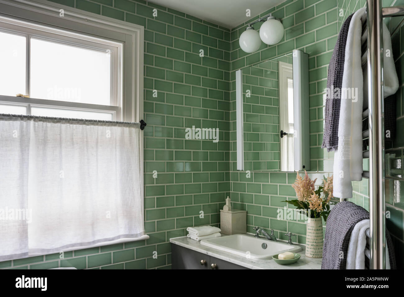 Greeen tiled bathroom with wall mounted cabinet Stock Photo