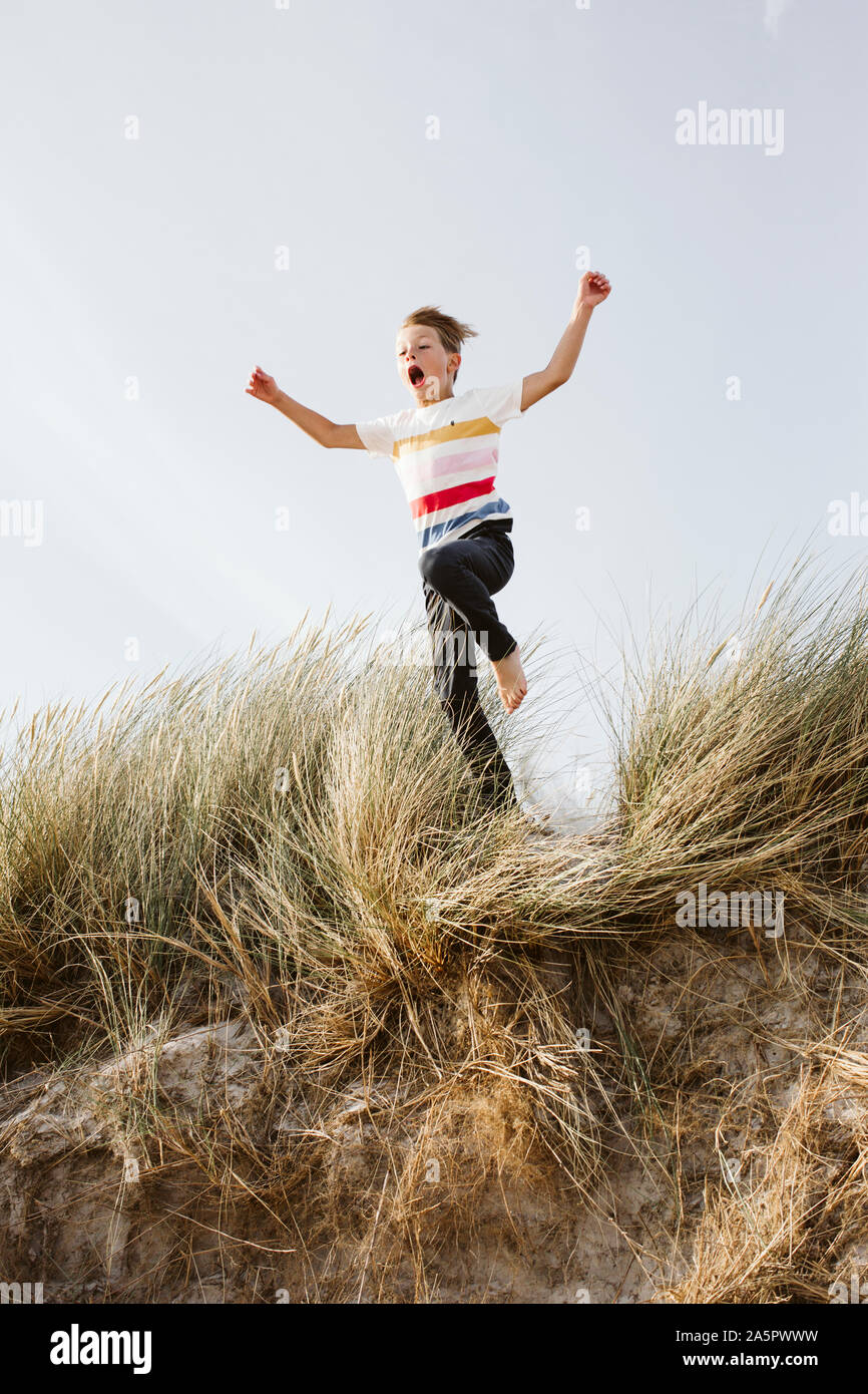Boy jumping on sand dune Stock Photo Alamy